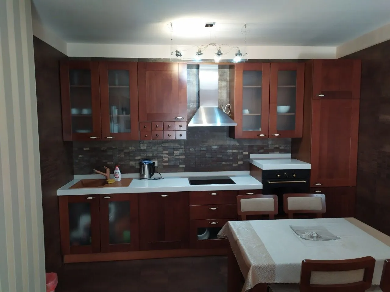 Kitchen with dark wooden cabinets and a dining table in the foreground.