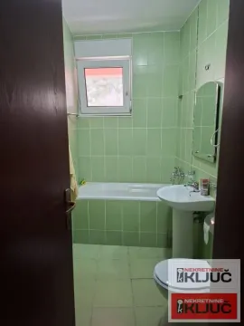 Kupatilo obloženo zelenim pločicama sa kadom, umivaonikom i toaletom. - image 10