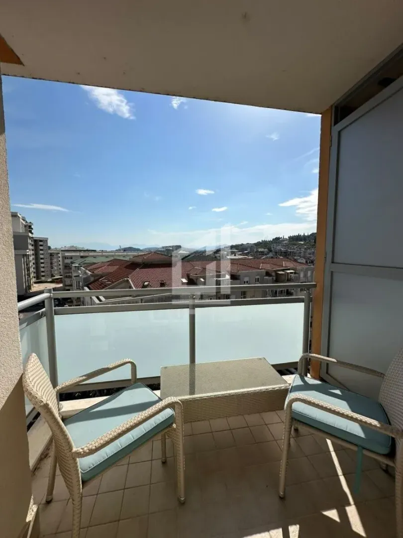 Natkriveni balkon sa garniturom za sedenje i pogledom na grad.