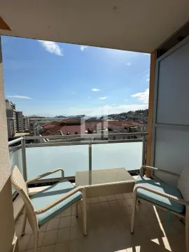 Natkriveni balkon sa garniturom za sedenje i pogledom na grad. - image 9