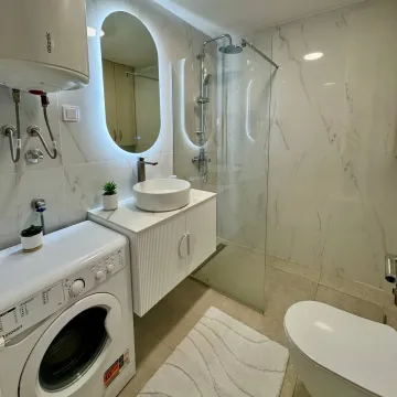 Savremeno opremljeno kupatilo sa tuš kabinom, umivaonikom i veš mašinom. - image 7