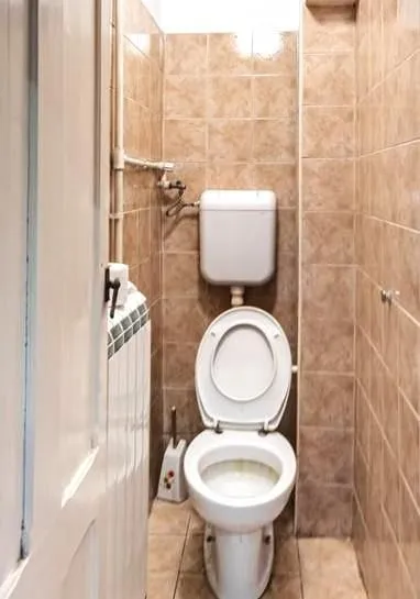 Manje kupatilo obloženo keramičkim pločicama sa WC šoljom.