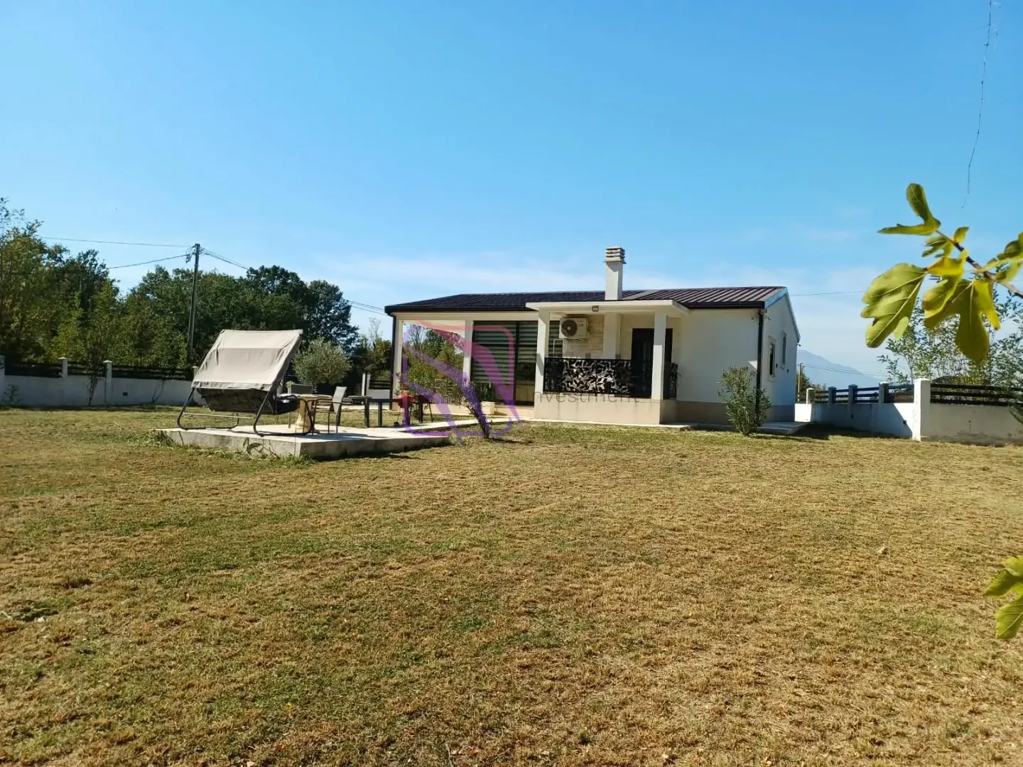 Exterior view of the house with a spacious yard and sun loungers.