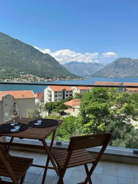Namješten balkon sa stolom, stolicama i čašama za vino i pogledom na more i planine. - image 9
