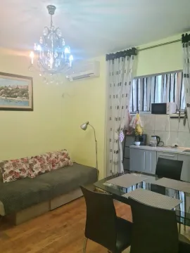 Dnevni boravak sa garniturom, trpezarijskim stolom i manjim kuhinjskim dijelom u pozadini. - image 3