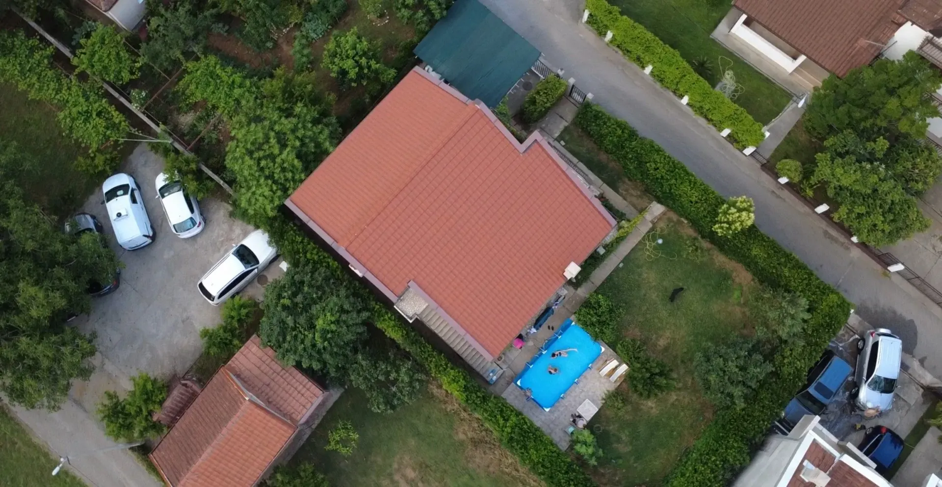 Aerial view of a house with a yard, swimming pool, and parking area.