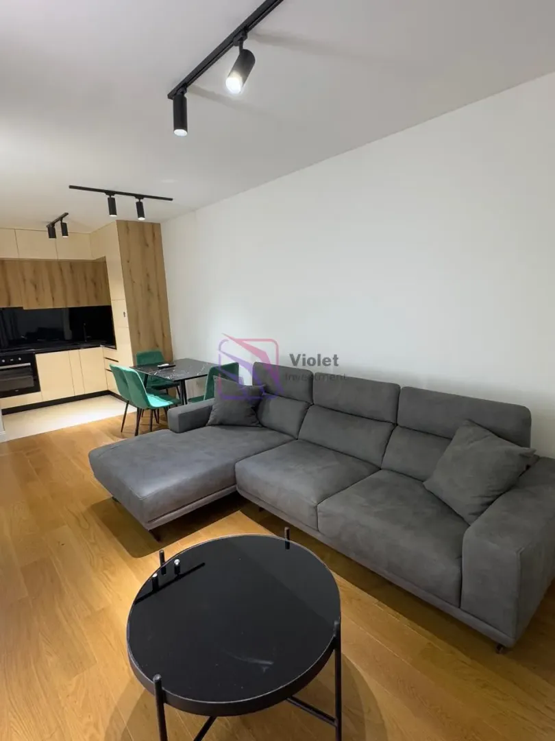 Living room with sofa, dining area, and kitchen in the background.
