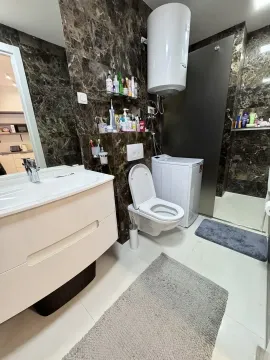 Moderne kupatilo sa umivaonikom, WC šoljom, veš mašinom i tuš kabinom obloženo tamnim mermernim pločicama. - image 18