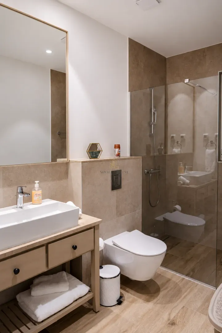 Moderne kupatilo sa umivaonikom, tuš kabinom i ugradnom wc šoljom.