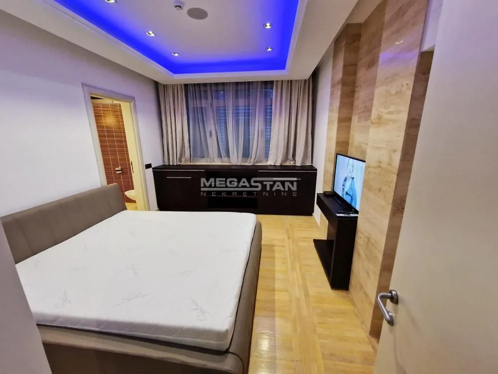 Furnished bedroom with a double bed, TV, and decorative lighting.