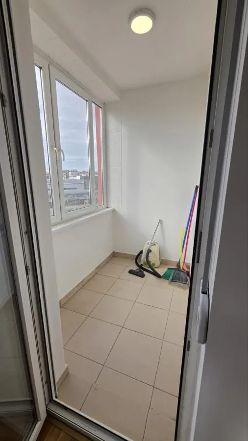 Zastakljeni balkon sa keramičkim pločicama na podu i priborom za čišćenje.