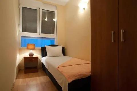 Mala spavaća soba sa jednim krevetom, noćnim ormarićem i ormarom. - image 13