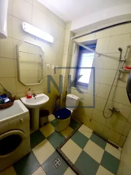Tiled bathroom equipped with a shower area, washbasin, toilet, and washing machine. - image 7
