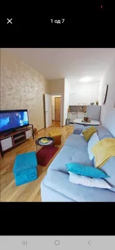 Living room with a sofa and dining area in the background. - image 6