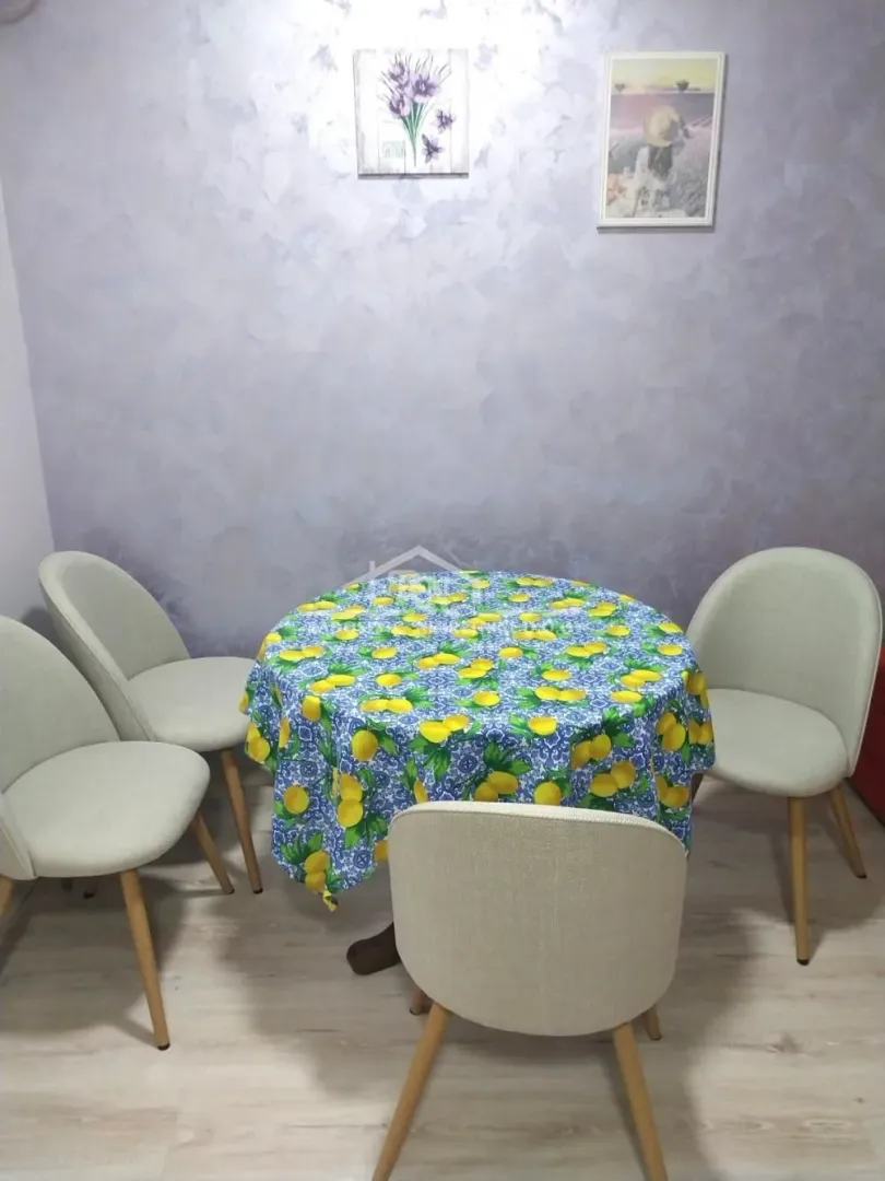 Trpezarijski sto sa četiri stolice i dekorativnim stolnjakom.
