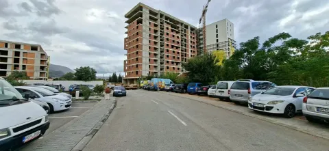 Pogled na ulicu sa parkiranim automobilima i višespratnicom u izgradnji u pozadini. - image 10