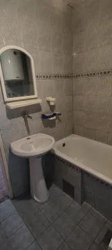 Smaller bathroom with a bathtub, washbasin, and mirror tiled with ceramic tiles. - image 7