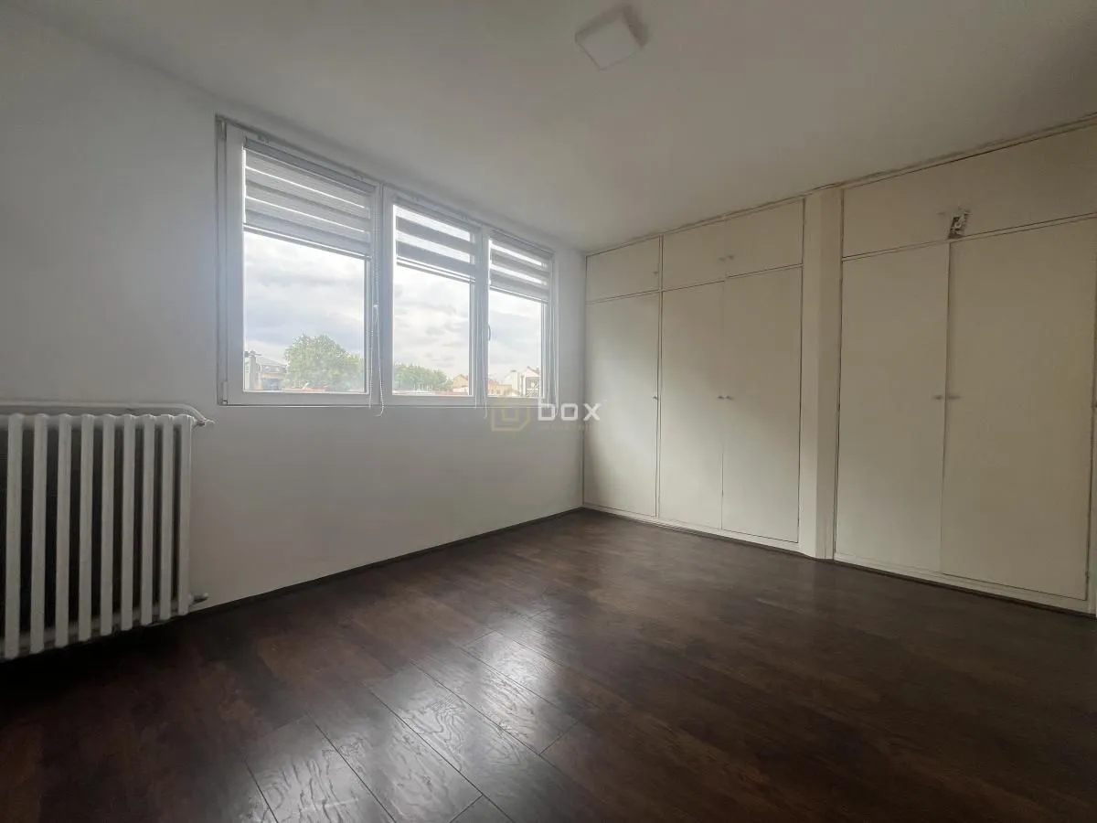 Empty bedroom with a built-in wardrobe and dark parquet flooring.