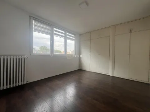 Empty bedroom with a built-in wardrobe and dark parquet flooring. - image 9
