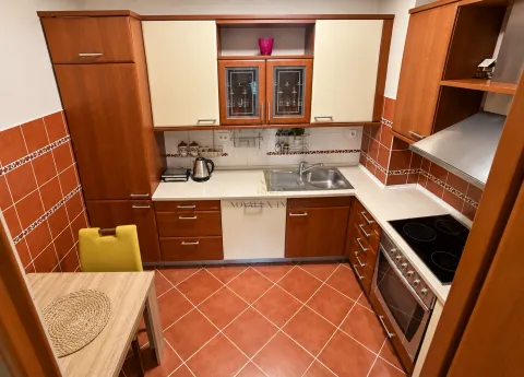 Kitchen equipped with wooden cabinets, a sink, a built-in cooktop, and a dining table. - image 4