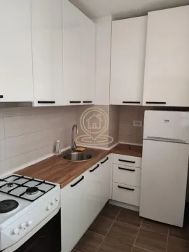 Manja opremljena kuhinja sa belim elementima, šporetom i frižiderom. - image 9