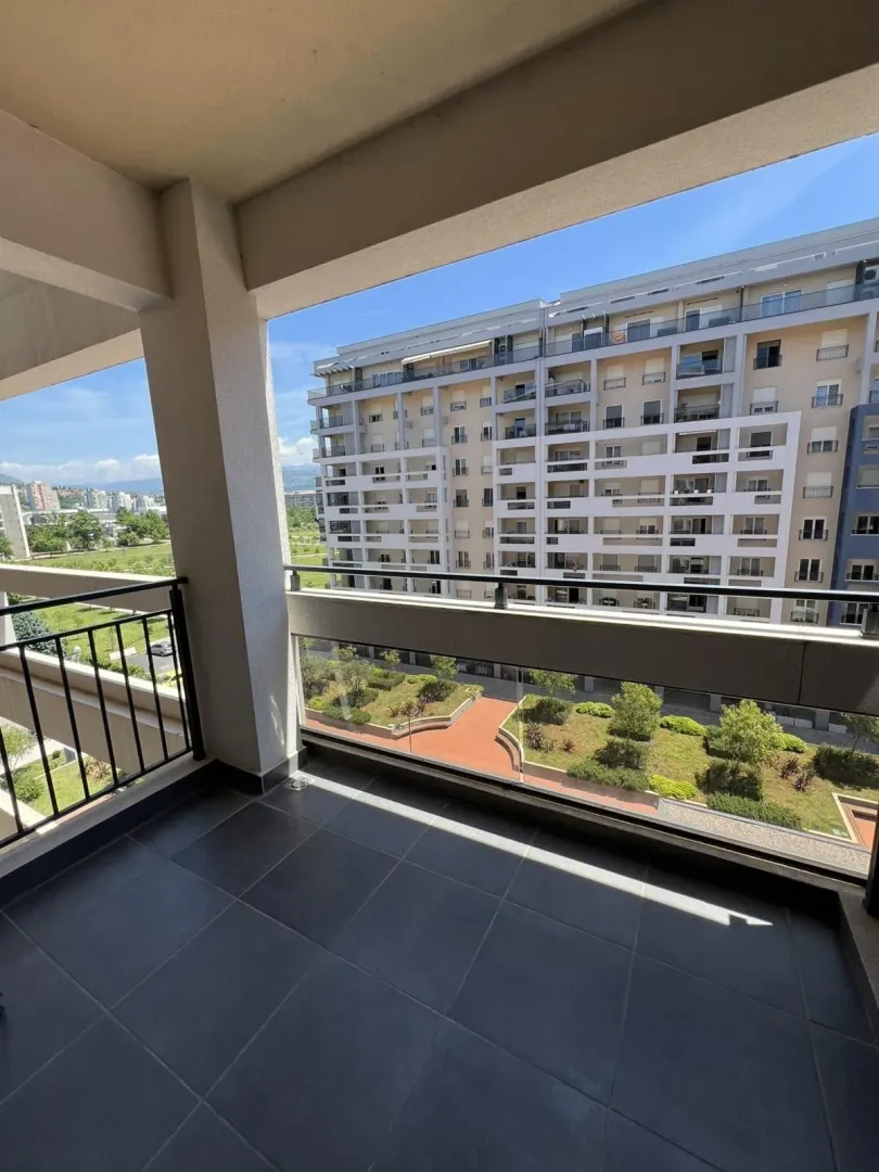 Prostrani balkon sa pogledom na uređeno dvorište i susjednu zgradu.