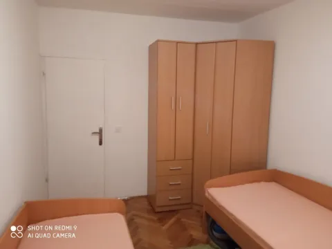 Simple bedroom with two beds and a corner wooden wardrobe. - image 12