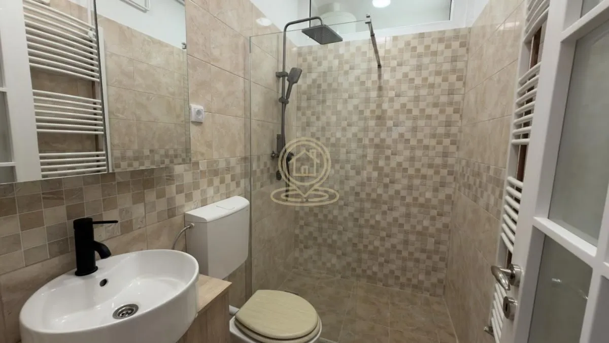 Kupatilo sa tuš kabinom, umivaonikom i wc šoljom obloženo keramičkim pločicama.