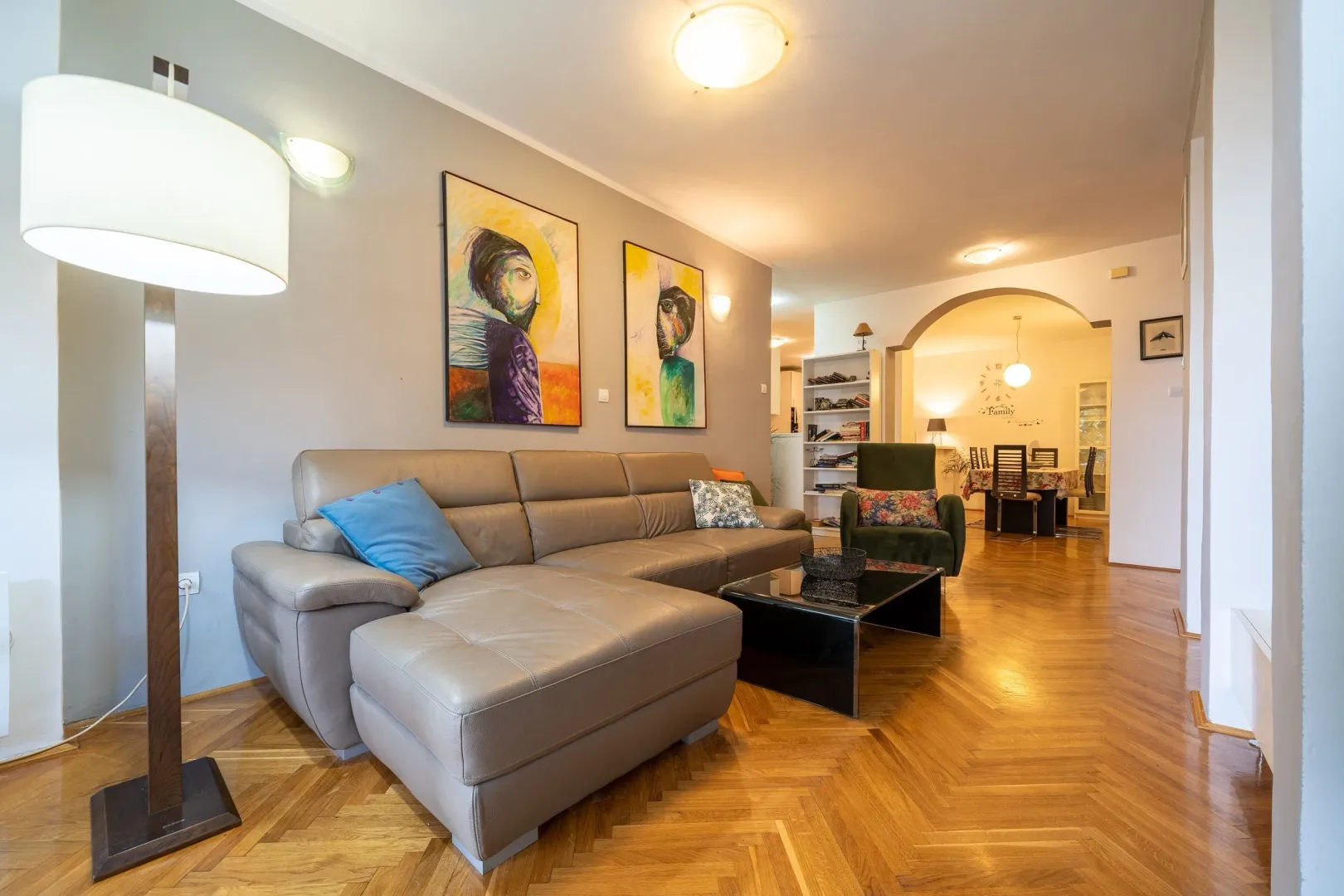 Spacious living room with a sofa and parquet flooring.