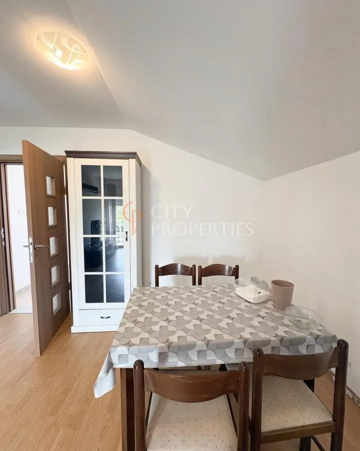 Dining area with a wooden table, chairs, and a white display cabinet in the attic.