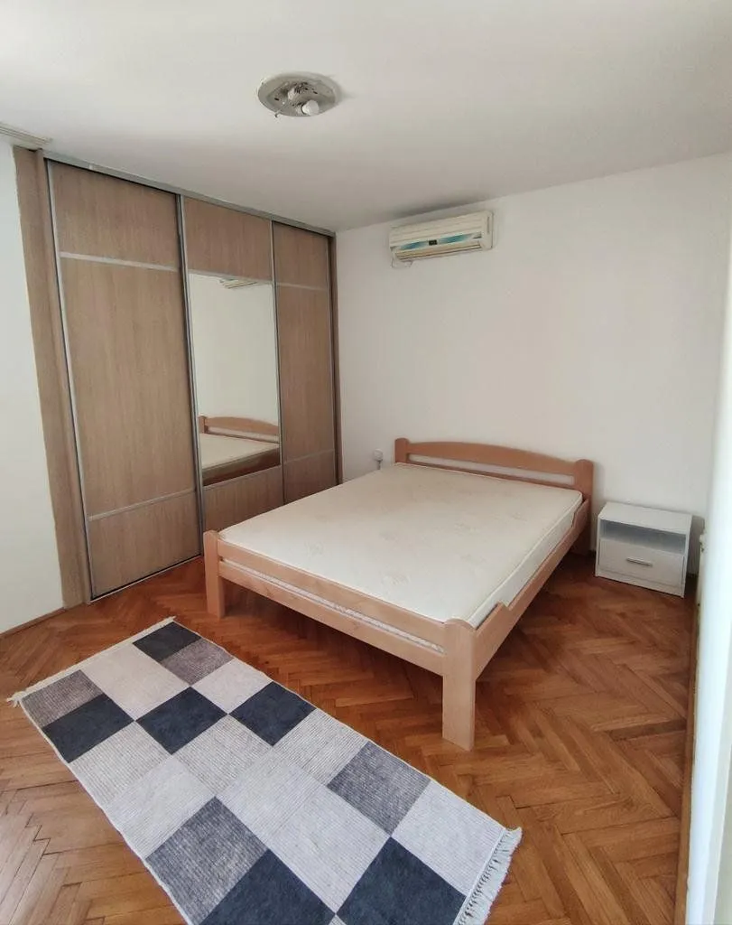 Bedroom with a double bed, wooden wardrobe, and parquet flooring.