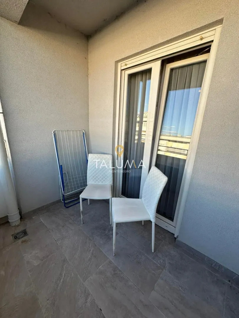 Manji popločani balkon sa dvije bijele stolice i sušačem za veš.