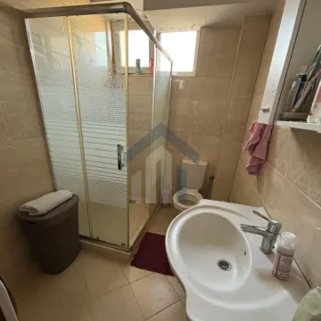 Small bathroom with a shower cabin, washbasin, and toilet in beige tiles. - image 15