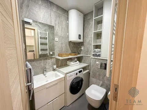 Modern bathroom with a sink, toilet, washing machine, and water heater. - image 9