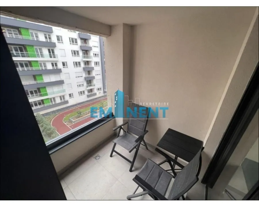 Covered balcony with a table and chairs and a view of surrounding buildings.