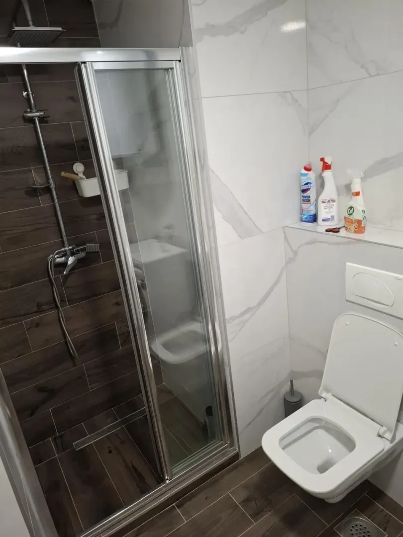 Modernly equipped bathroom with a shower cabin and toilet.