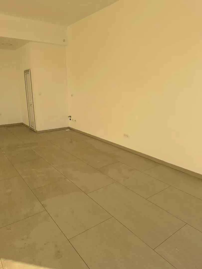 Empty room with ceramic floor tiles and light-colored walls.