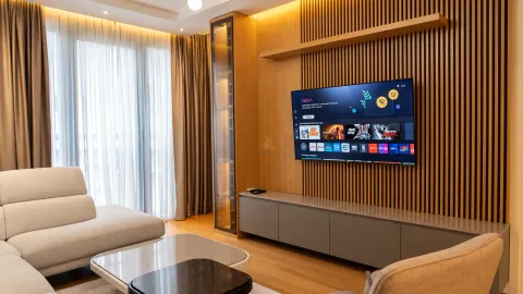 Living room with sofa, wall-mounted television, and wooden wall panels. - image 6