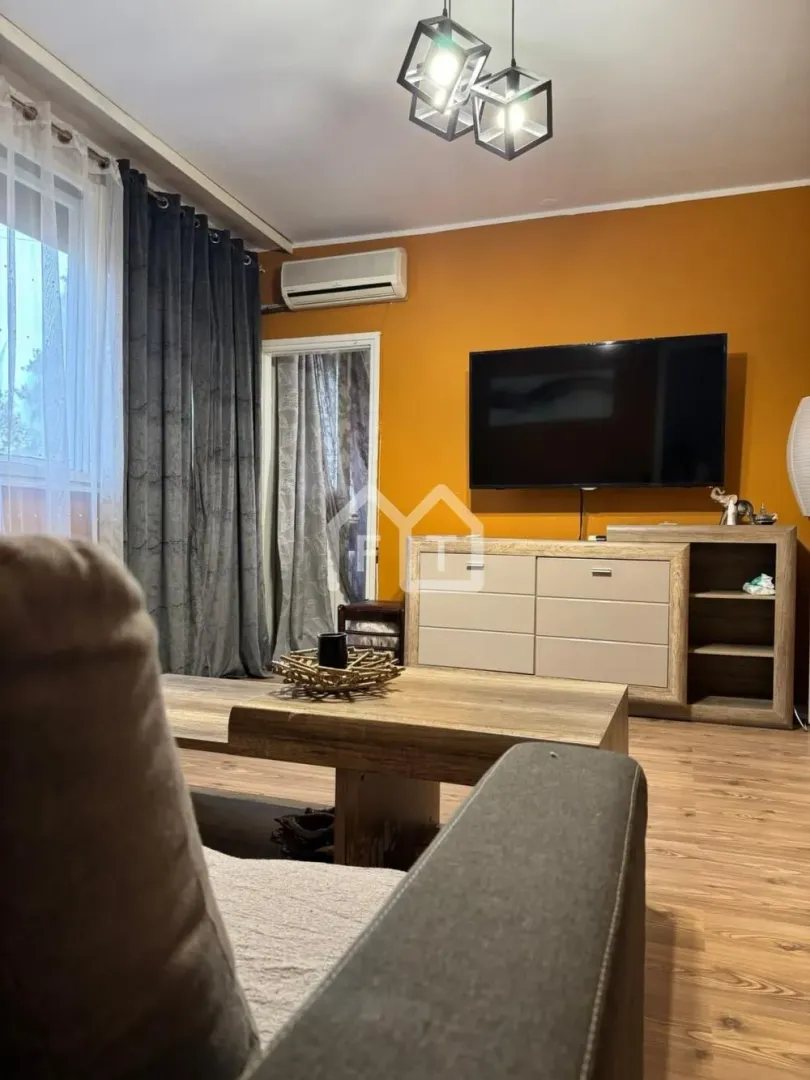 Living room with a sofa, TV unit, and an orange accent wall.