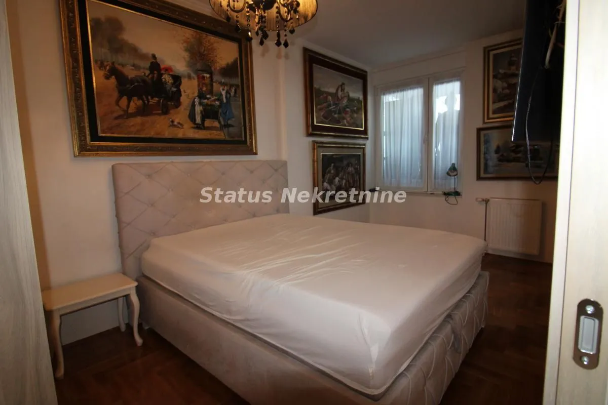 Furnished bedroom with a double bed and paintings on the wall.