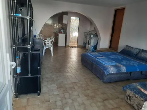Spacious living room with a bed and a view of the kitchen in the background. - image 7