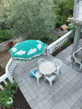 Tiled terrace with seating furniture and a sun umbrella in the yard. - image 3