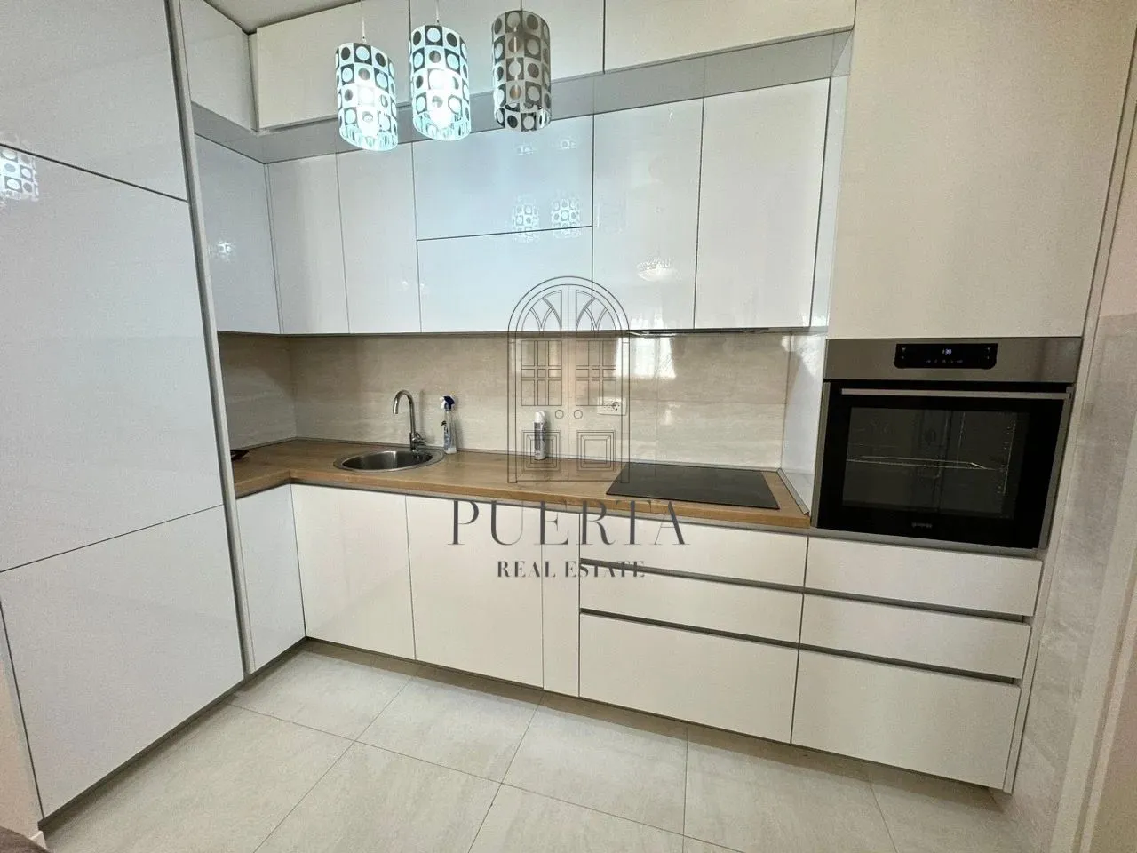 Modern white kitchen with built-in appliances and a wooden countertop.