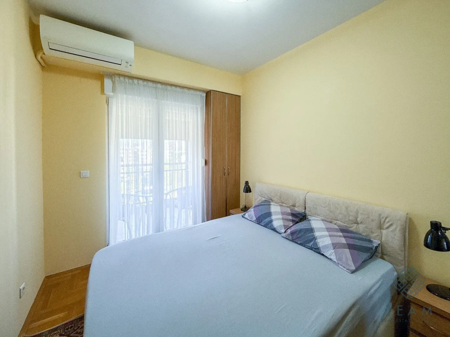 Furnished bedroom with a double bed, air conditioning, and balcony access.