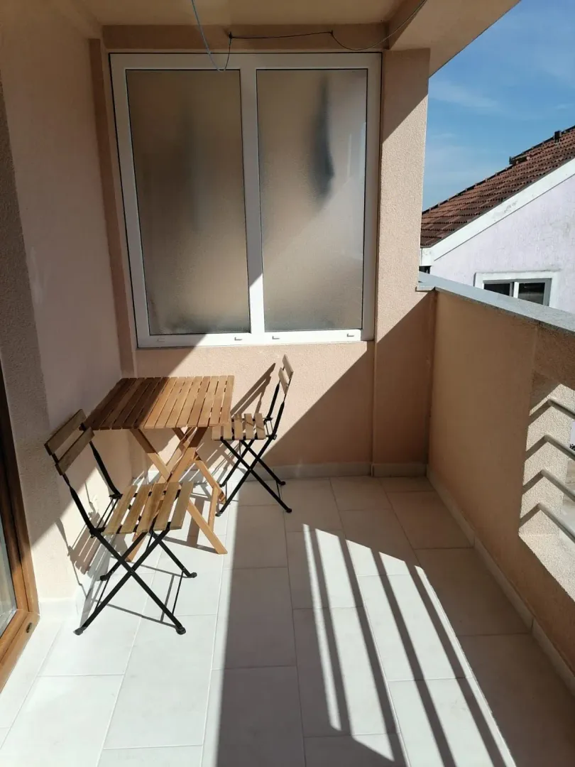 Manji natkriveni balkon sa drvenim stolom i dvije stolice.