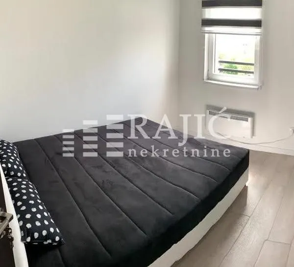 Bedroom with a double bed, window, and laminate flooring.