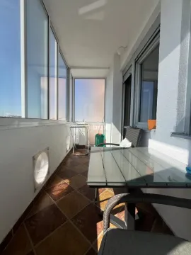 Enclosed balcony with a table, chairs, and tiled flooring. - image 11