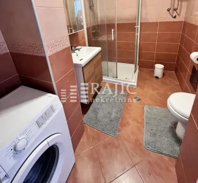 Tiled bathroom featuring a shower cabin, washbasin, and washing machine. - image 10