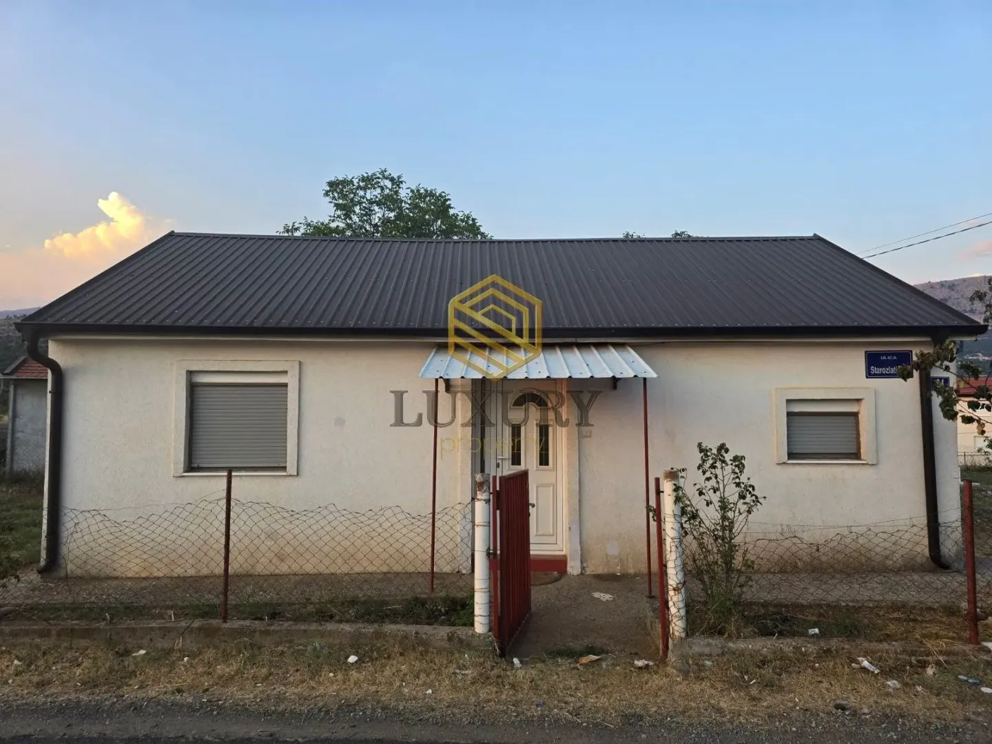 Front view of a single-story house with a yard and a fence.