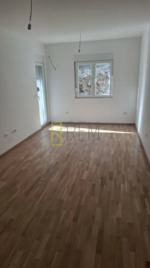 Prazna soba sa parketom i bijelim zidovima.